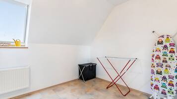 Une pièce équipée d’un radiateur, d’un étendoir, d’un petit meuble de rangement noir et d’une fenêtre donnant sur un paysage agréable.