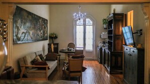Un salon comprenant un canapé, des fauteuils, une table à manger et un téléviseur posé sur un meuble.