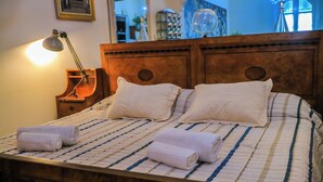 Un lit bien fait, avec une couvre-lit à rayures et deux oreillers, une tête de lit en bois et une lampe de chevet.