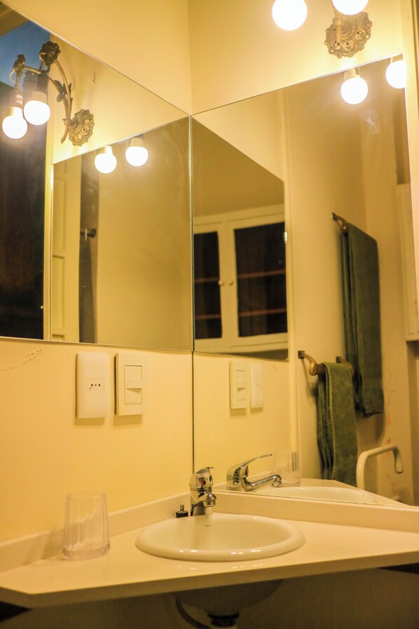 A bathroom with a large mirror, a sink, and a window.