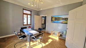 A dining area with a table, chairs, a vase, and a painting on the wall.