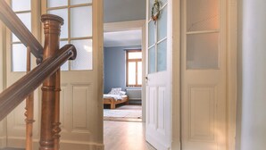 A wooden staircase leading to a bedroom with a bed and a radiator.