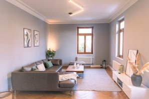 A modern living room with a grey sofa, a wooden coffee table, and a white console table with a vase.