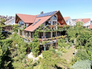 A multi-story house with a sloped roof, solar panels, and a balcony with plants. - Apartment "Reblaube" with Private Terrace and Wi-Fi (Radolfzell am Bodensee)