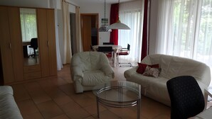 Een woonkamer met een bank, fauteuil en een glazen salontafel.