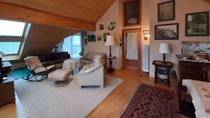 Un loft spazioso con soffitto alto, un'ampia finestra, una zona salotto accogliente e un angolo cottura.