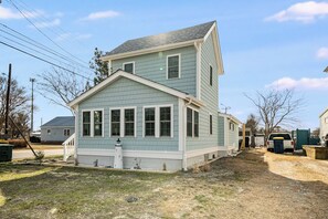 A two-story house with a front porch and a small garden area. - Mariner's Light by Seaside Vacations & Sales (Chincoteague Island)
