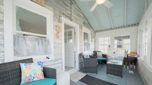 A cozy, well-lit room with a ceiling fan, wicker furniture, and a small table with a decorative horse statue. - Mariner's Light by Seaside Vacations & Sales (Chincoteague Island)