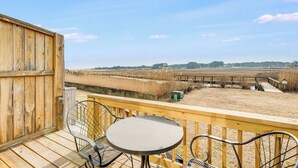 Um deck de madeira com mesa e cadeiras com vista para um campo.