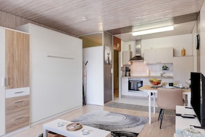 A modern kitchen with white cabinets, a stove, and a dining area with a table and chairs.
