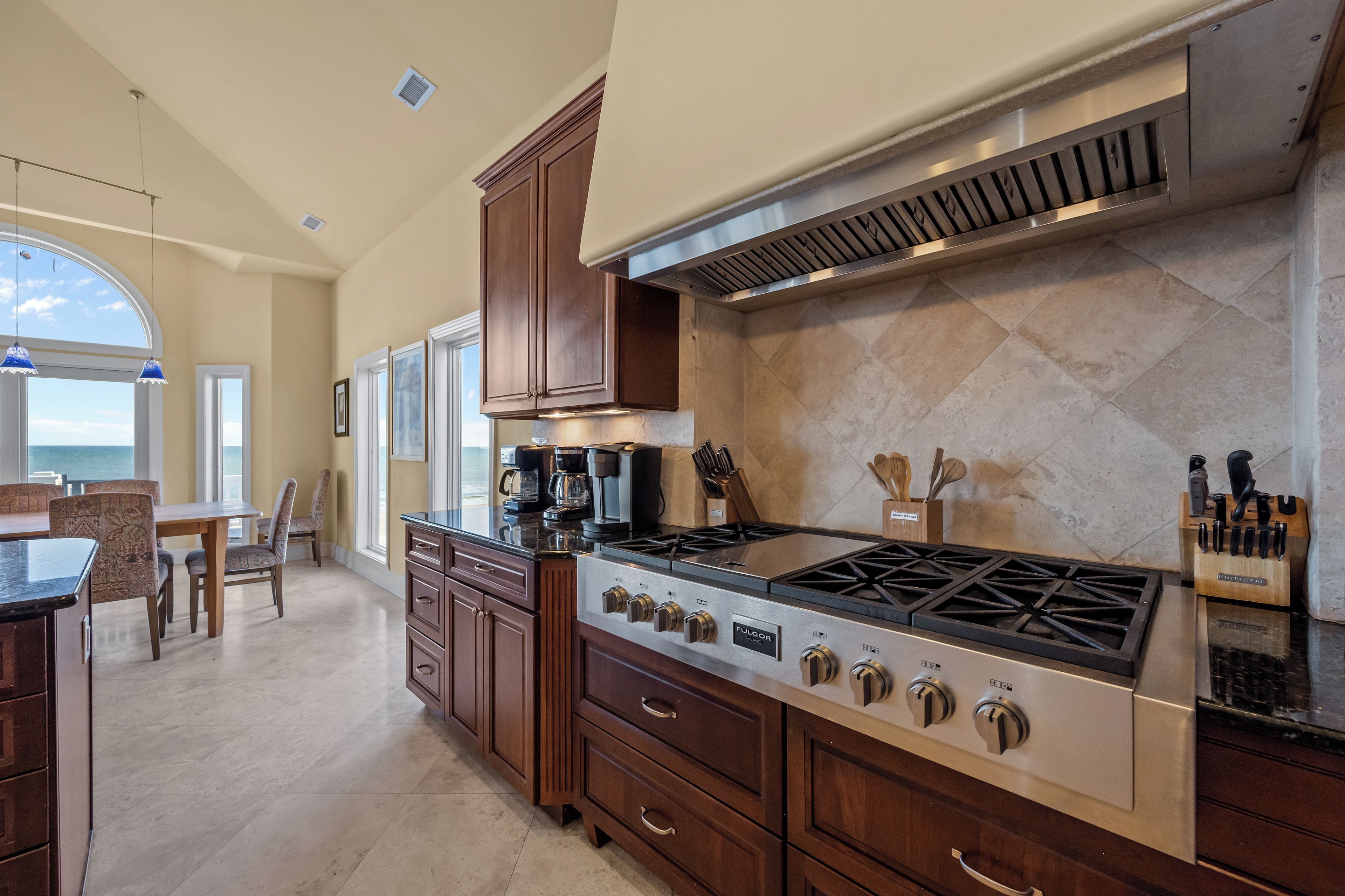 A modern kitchen with a large island, built-in cabinets, and a gas stove.