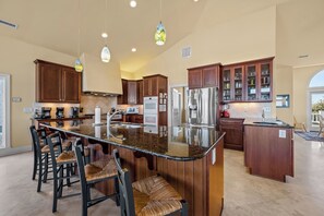 A spacious kitchen with a large island, dark wooden cabinets, and modern appliances. - La Grande Dame - Oceanfront 8BR, Private Pool, Elevator, Game Room + Theater (North Topsail Beach)