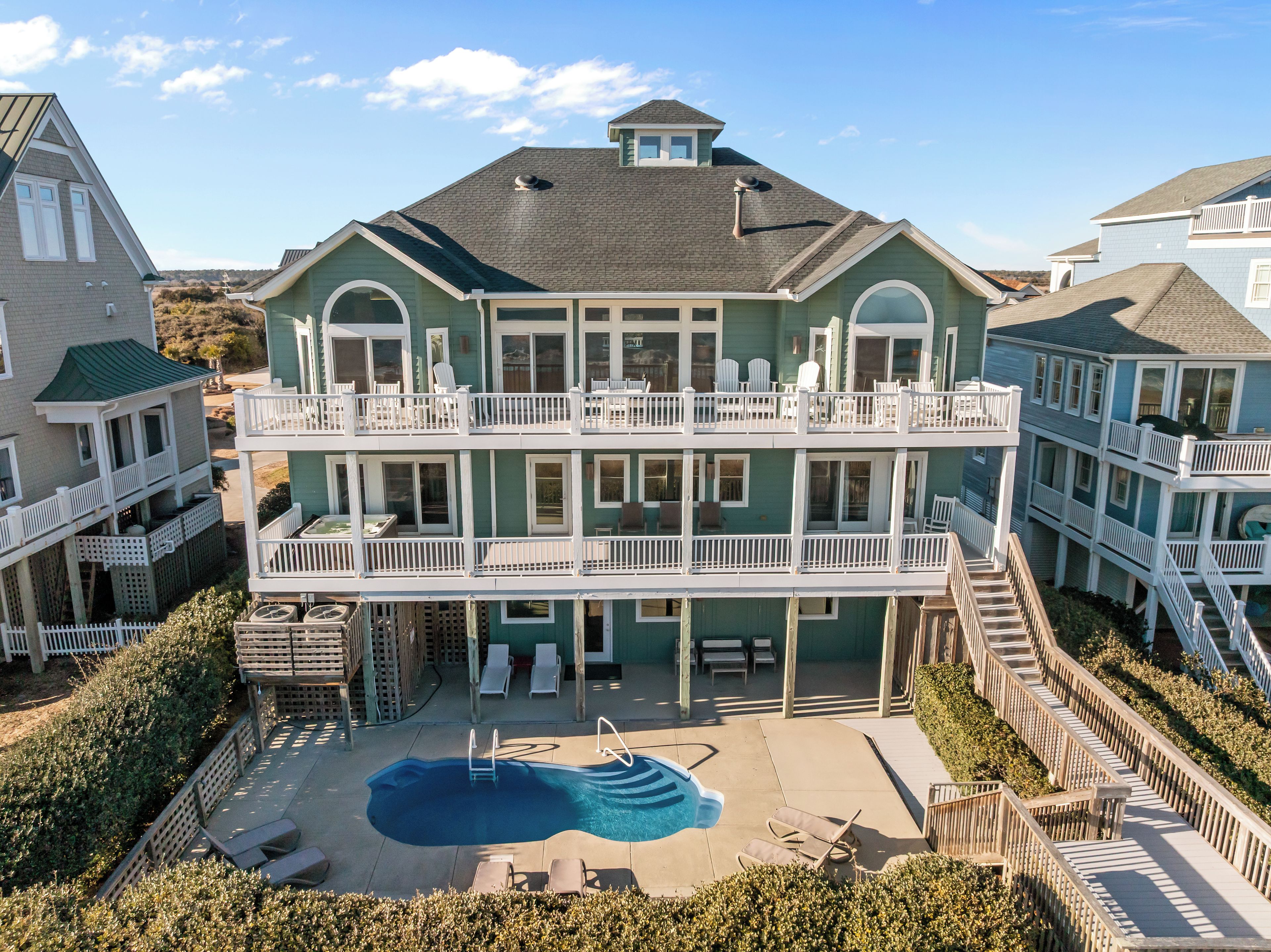 A large two-story building with a swimming pool, multiple balconies, and a covered patio area.