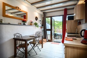 A kitchen with a wooden table, chairs, and a red kettle. - La Petite Maison De Vacances with Terrace in Kaysersberg (Kaysersberg Vignoble)