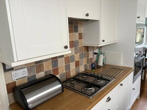 A kitchen with white cabinets, a gas stove, a toaster, and a tiled backsplash. - Wolves Retreat Sleeps 7 With Garden Parking (Wolverhampton)