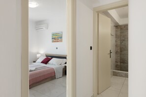 Un dormitorio con cama, mesita de noche, aire acondicionado de pared y un cuadro.