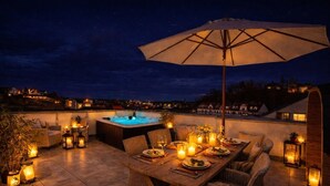 A rooftop terrace with a hot tub, dining table, chairs, and lanterns. - The Summit Rooftop Spa Meissen – Exclusive Penthouse with Jacuzzi & Sauna (Meißen)