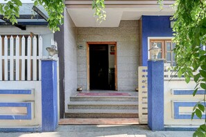 A building entrance with a white picket fence, a blue and beige wall, and a set of steps leading to a door.