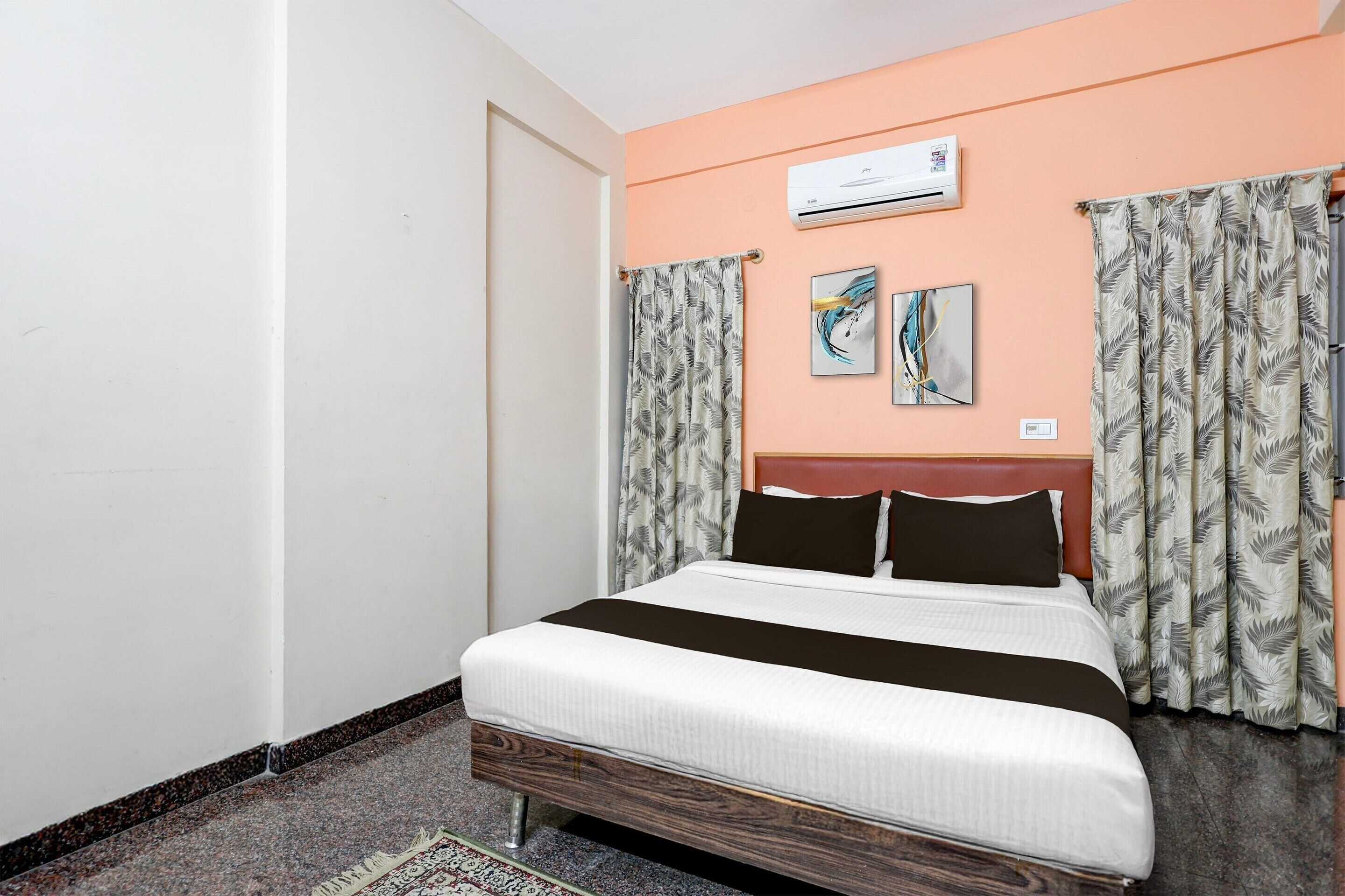 Habitación de hotel con cama, aire acondicionado, una obra de arte, cortinas y alfombra.