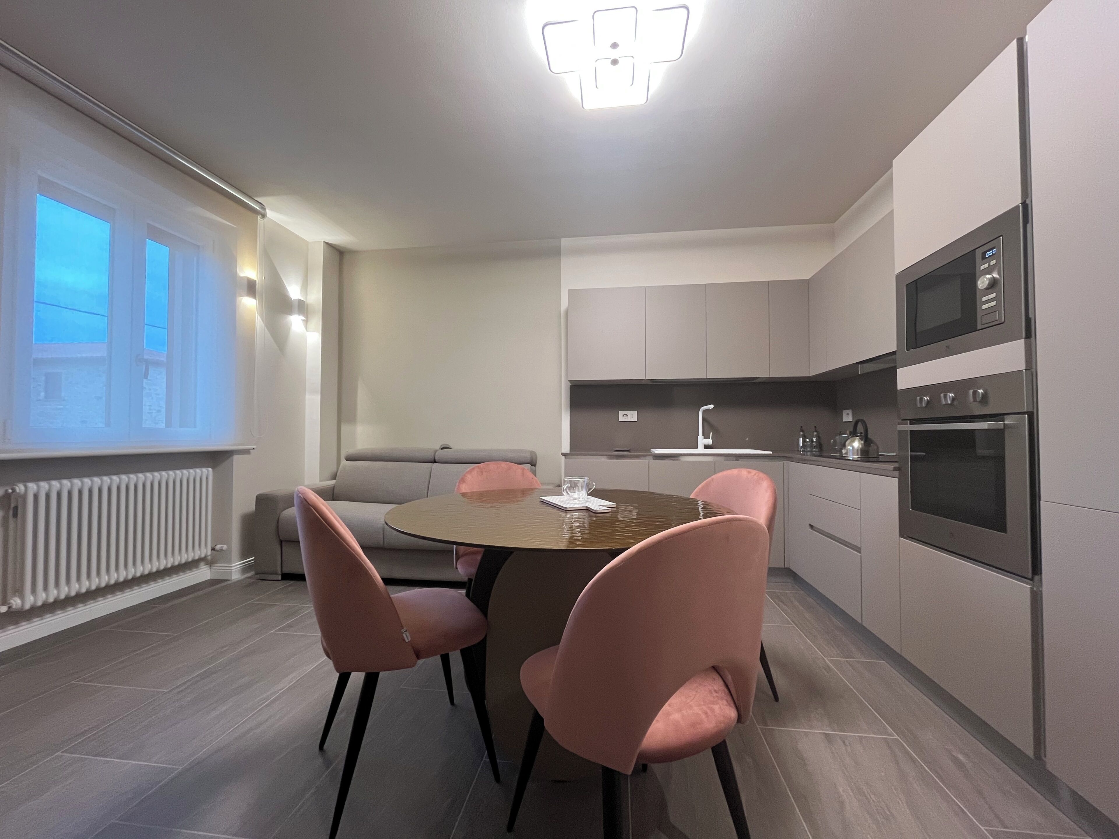 A modern kitchen with a dining table and chairs, a built-in oven, and a microwave.
