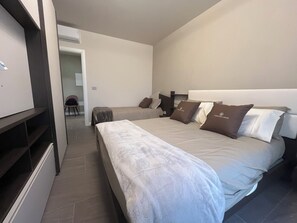 A hotel room with a large bed, a bedside table, a wardrobe, and a bathroom visible through an open door.