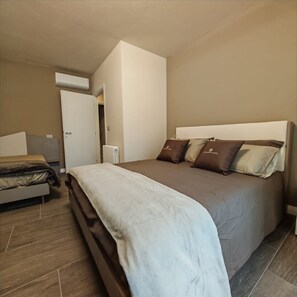 A bedroom with a large bed, a smaller bed, and a radiator.