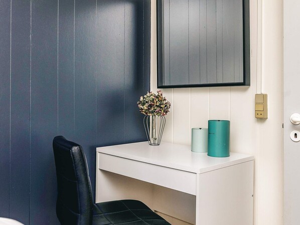 A room with a white desk, a black chair, a wall-mounted TV, and a vase with flowers. - 6 Person Holiday Home in Logstor (Logstor)