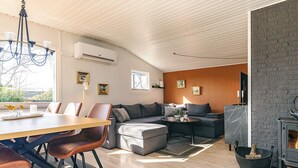 A modern living room with a dining area, a fireplace, and a view through a window. - 6 Person Holiday Home in Logstor (Logstor)
