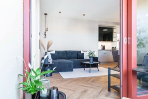Ein modernes Wohnzimmer mit einer Couch, einem kleinen runden Tisch und einem Blumentopf.
