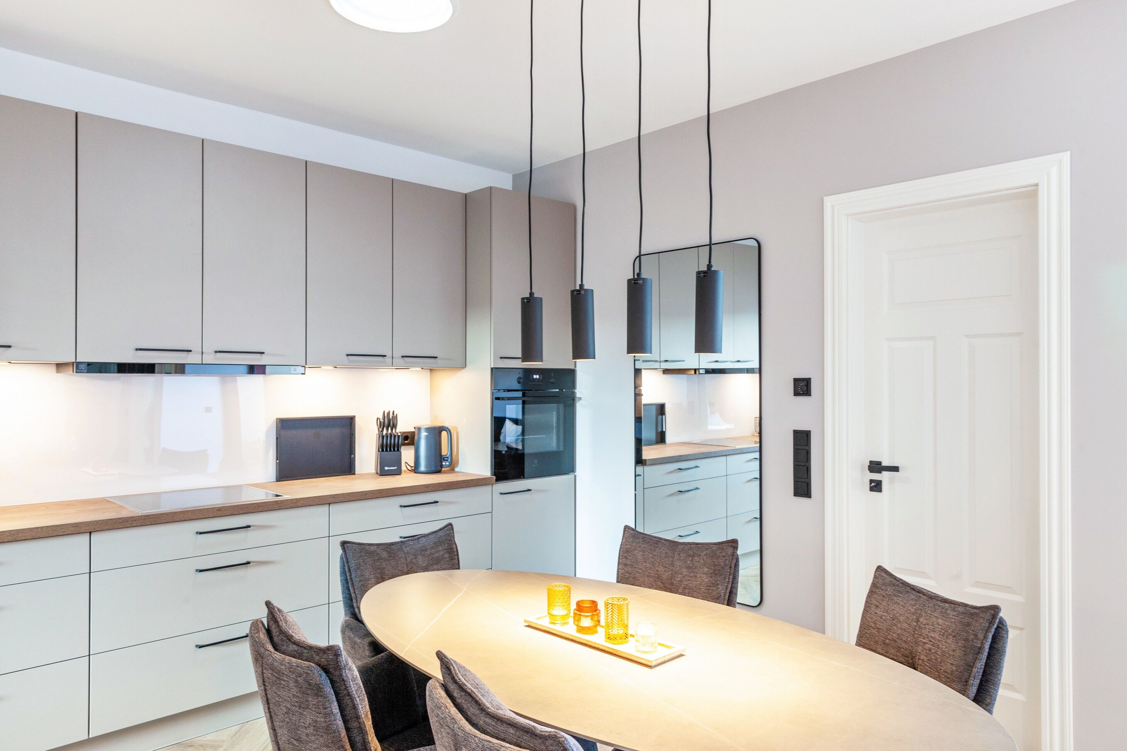 Une cuisine moderne avec une table à manger, des chaises et des luminaires suspendus.