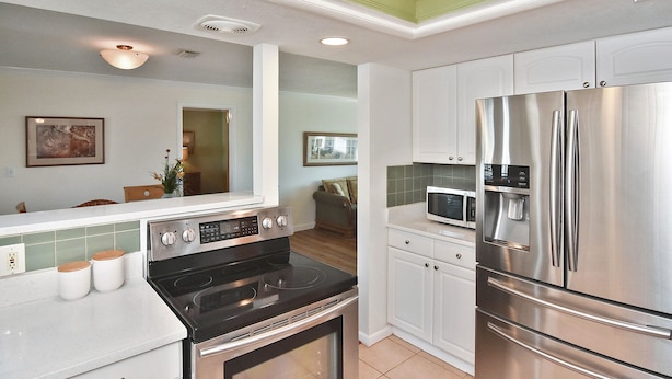 Ett modernt kök med ett kylskåp i rostfritt stål, en inbyggd mikrovågsugn och en svart spis.