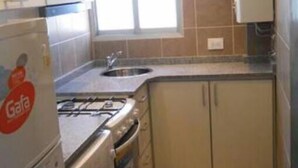 Eine kleine Küche mit eingebautem Herd, Backofen und Waschmaschine, einem Fenster und einem Spülbecken.