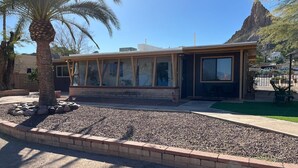 Un edificio moderno con amplios ventanales, fachada de piedra y un área ajardinada con una palmera.