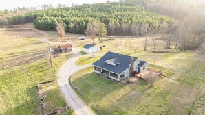 An aerial view of a rural property with a large house, a driveway, and surrounding fields. - Stunning Views Gated Mountain Retreat 20 Acres (Garland County)