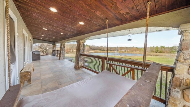 A covered outdoor area with stone pillars, a wooden deck, and a view of a lake. - Stunning Views Gated Mountain Retreat 20 Acres (Garland County)