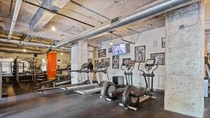 Un gimnasio con cintas de correr, elípticas y equipo de levantamiento de pesas.
