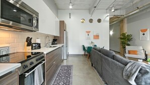 Una cocina compacta con electrodomésticos modernos, un rincón de comedor con un sofá y una pequeña mesa.