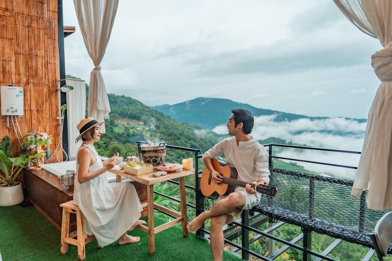 Una pareja cenando en un balcón con vistas panorámicas a la montaña.