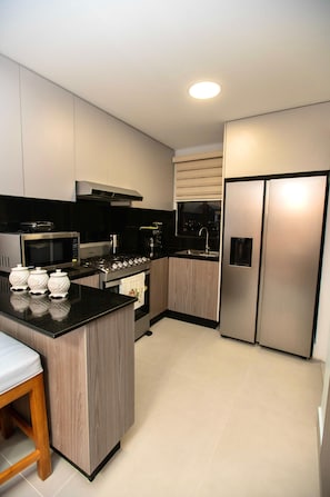 A modern kitchen with a central island, stainless steel appliances, and a built-in oven. - Beautiful Lodging with Terrace and Jacuzzi in Santiago. (Santiago de los Caballeros)