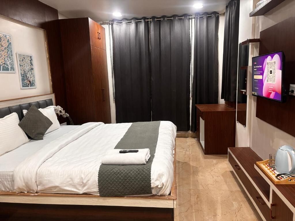 A hotel room with a bed, a TV, a desk, and a coffee machine.