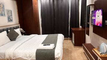 A hotel room with a bed, a TV, a desk, and a coffee machine.