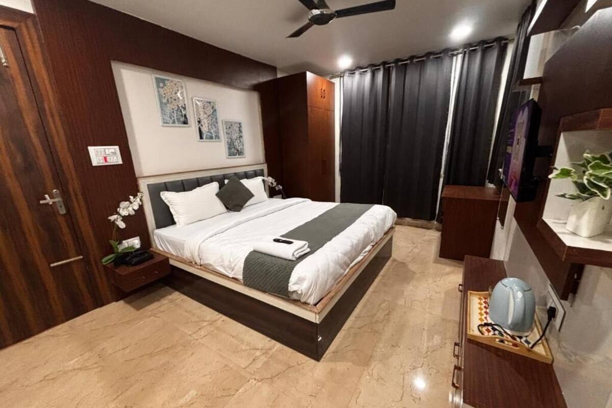 Un dormitorio moderno con cama, mesita de noche, ventilador de techo y escritorio con hervidor.