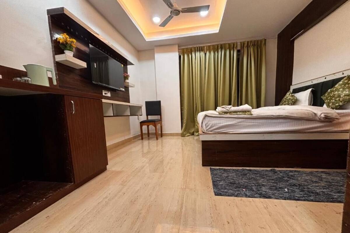 Un dormitorio moderno con cama, escritorio, silla, televisor y ventilador de techo.