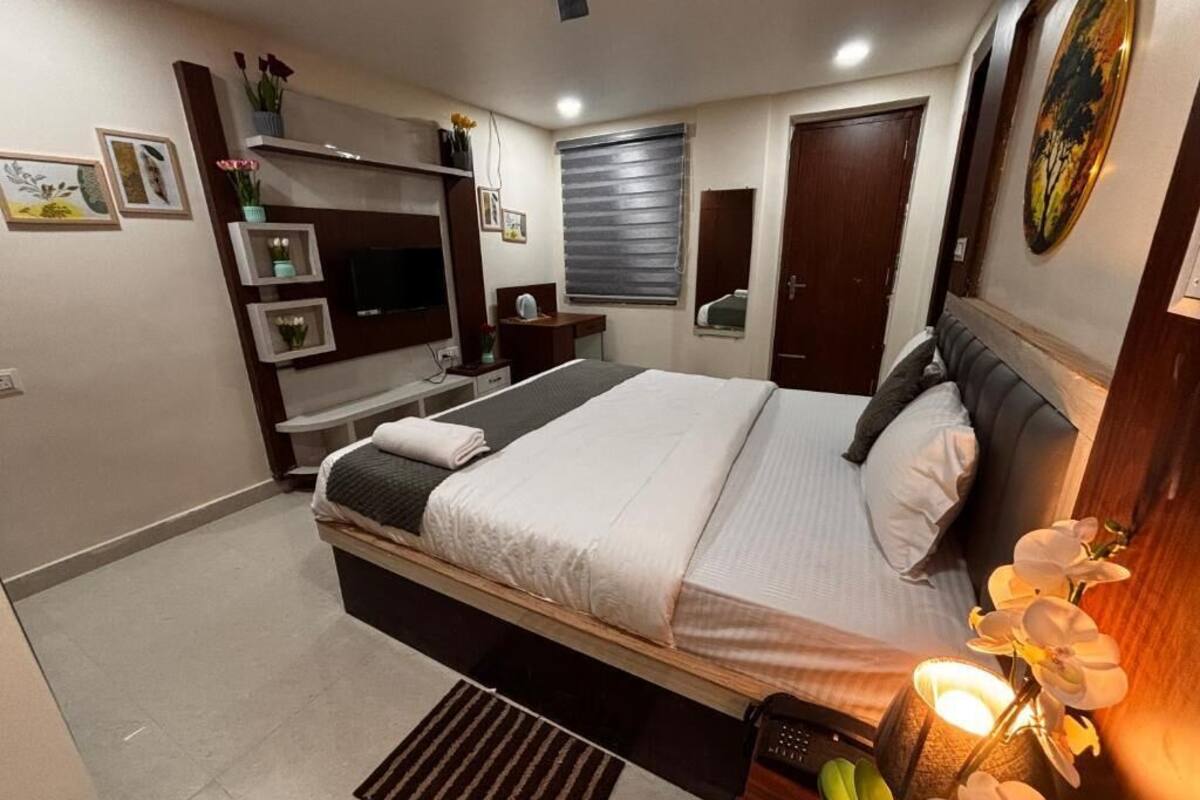 Un dormitorio moderno con cama, mesitas de noche, televisor y ventana con persianas.