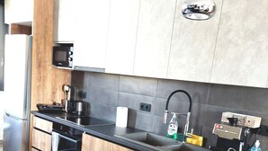 A modern kitchen with a central island, dark countertops, and wooden cabinetry. - Zenozy Luxury Apartments - Corfu Town (Kerkira)
