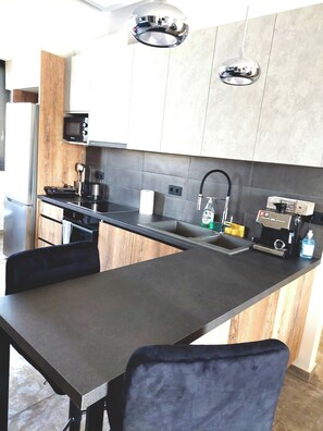 A modern kitchen with a central island, dark countertops, and wooden cabinetry. - Zenozy Luxury Apartments - Corfu Town (Kerkira)