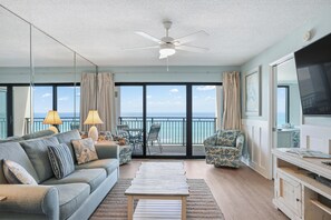 Ein geräumiger Balkon mit Meerblick, ausgestattet mit einer Couch, Stühlen und einem Tisch.