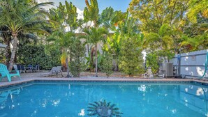 Una piscina rodeada de plantas tropicales y mobiliario de exterior.