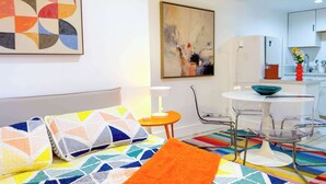 Un apartamento moderno con una cama, una pequeña mesa redonda y una zona de cocina.