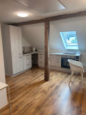 Una cocina moderna con suelo de madera, tragaluz y zona de comedor blanca.